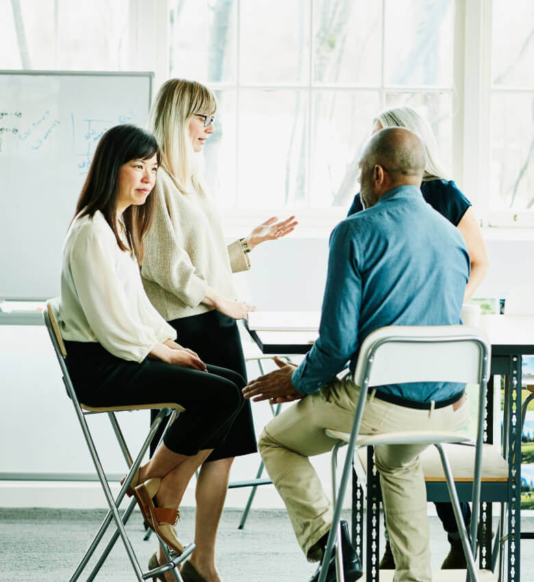 A group of employees in a conference room talking and working. 