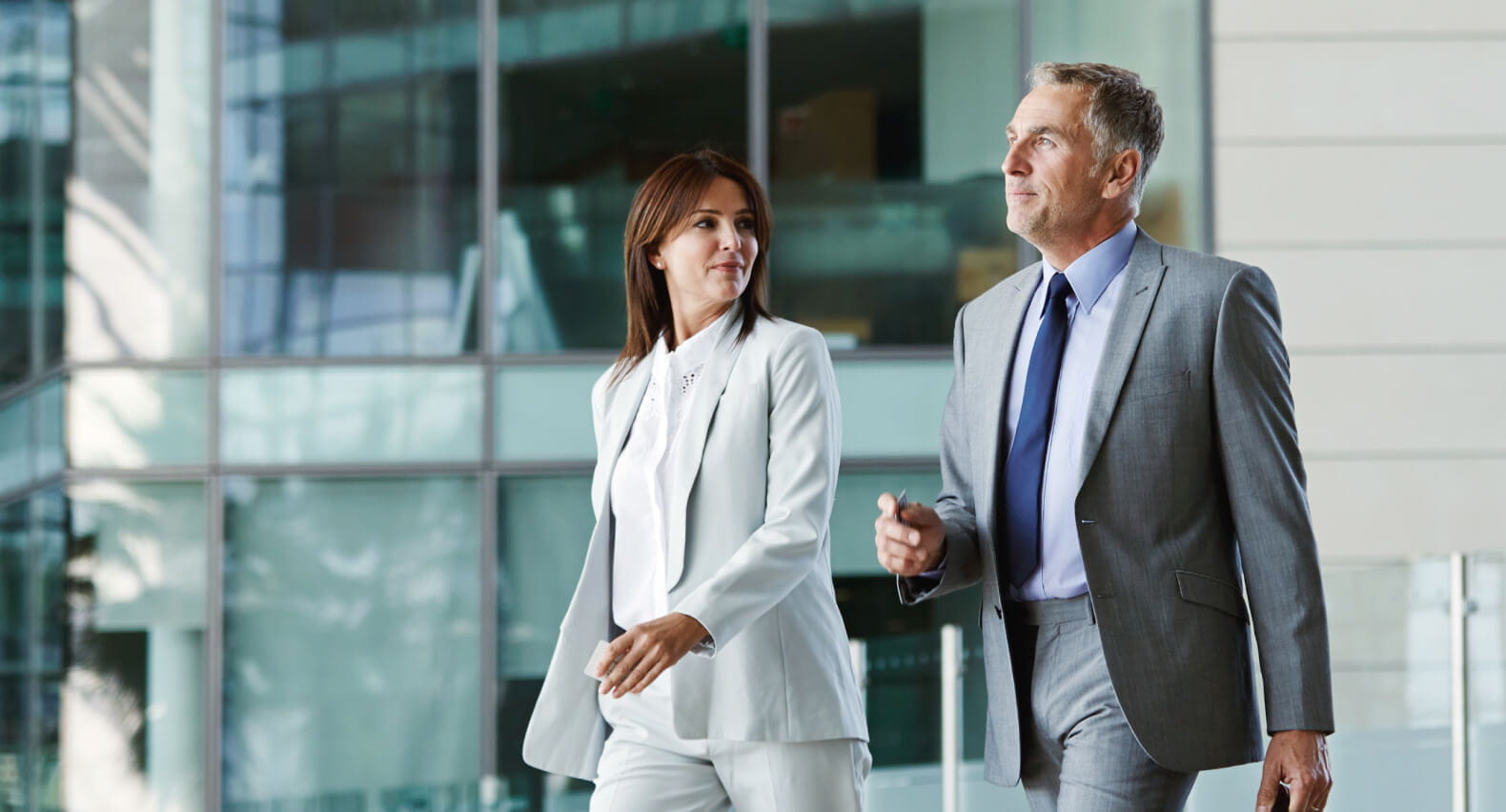 A man and a woman in suits walking. 