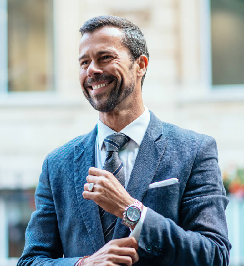 A man in a navy blue suit wearing a watch. 