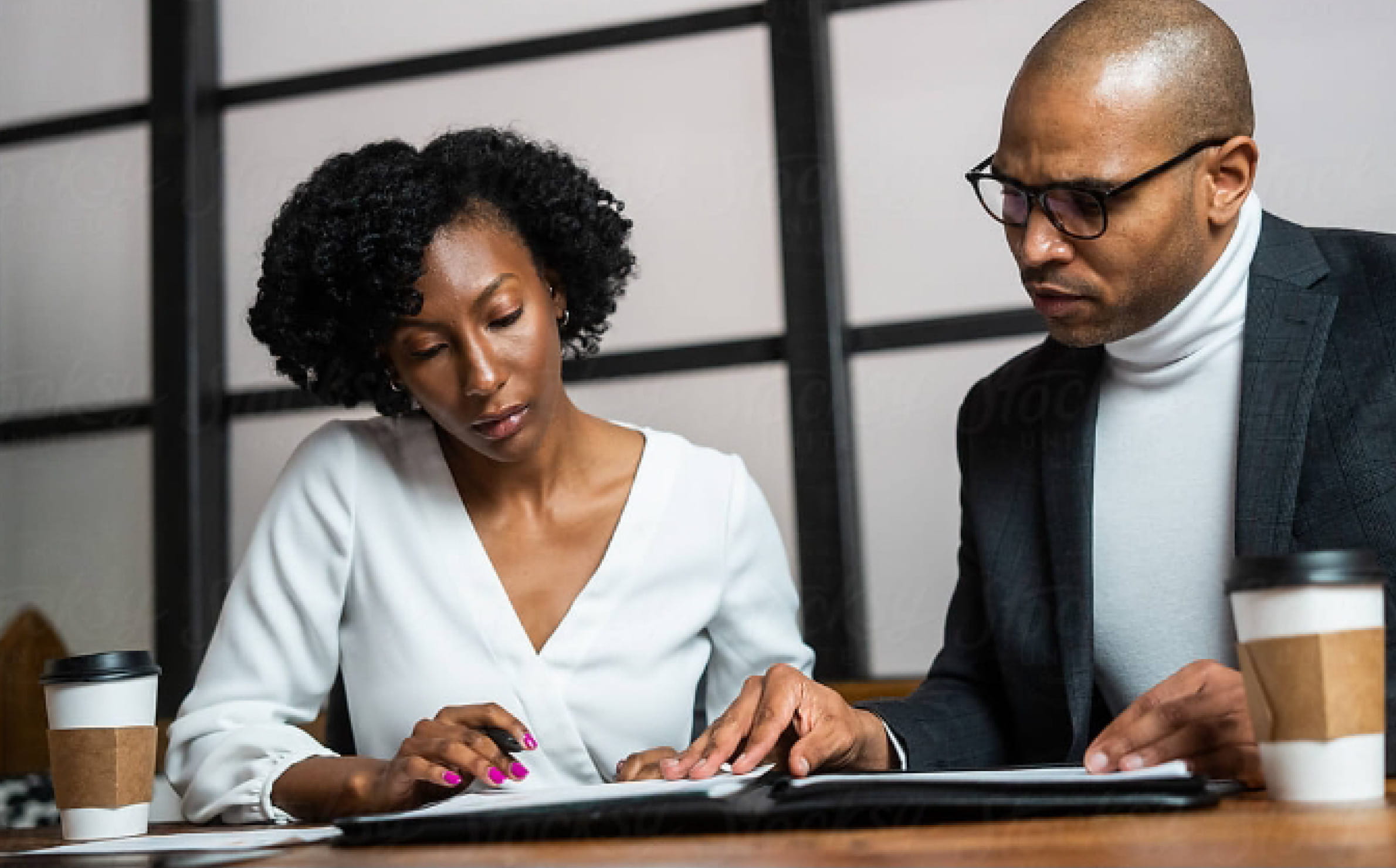 An advisor and investor review paperwork together in an office